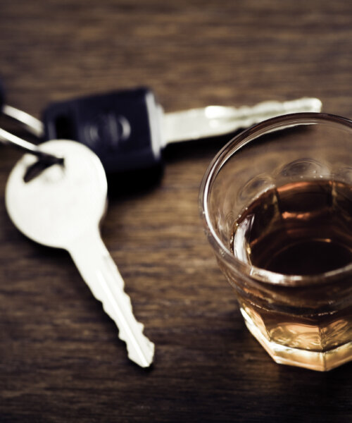 Car keys next to a glass of whiskey to represent drunk driving